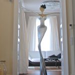 A white and blue glass sculpture featuring a woman elegantly posed on its surface.