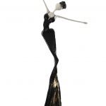 A black and gold sculpture depicting a woman elegantly dressed in a flowing gown.