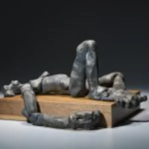 A sculpture depicting a man reclining on a wooden box, showcasing intricate details and a serene expression.
