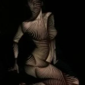 A woman with her body painted in vivid red and black stripes, highlighting a creative and expressive artistic style.