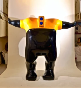 A large black and yellow statue of a man stands prominently, showcasing intricate details and a striking color contrast.