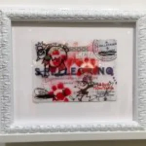 A framed picture of a cat hanging on a wall, showcasing the cat's playful expression and vibrant colors.