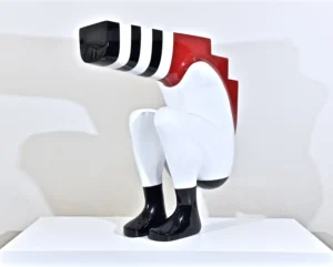 A sculpture depicting a man seated on a white base, showcasing intricate details and a contemplative expression.